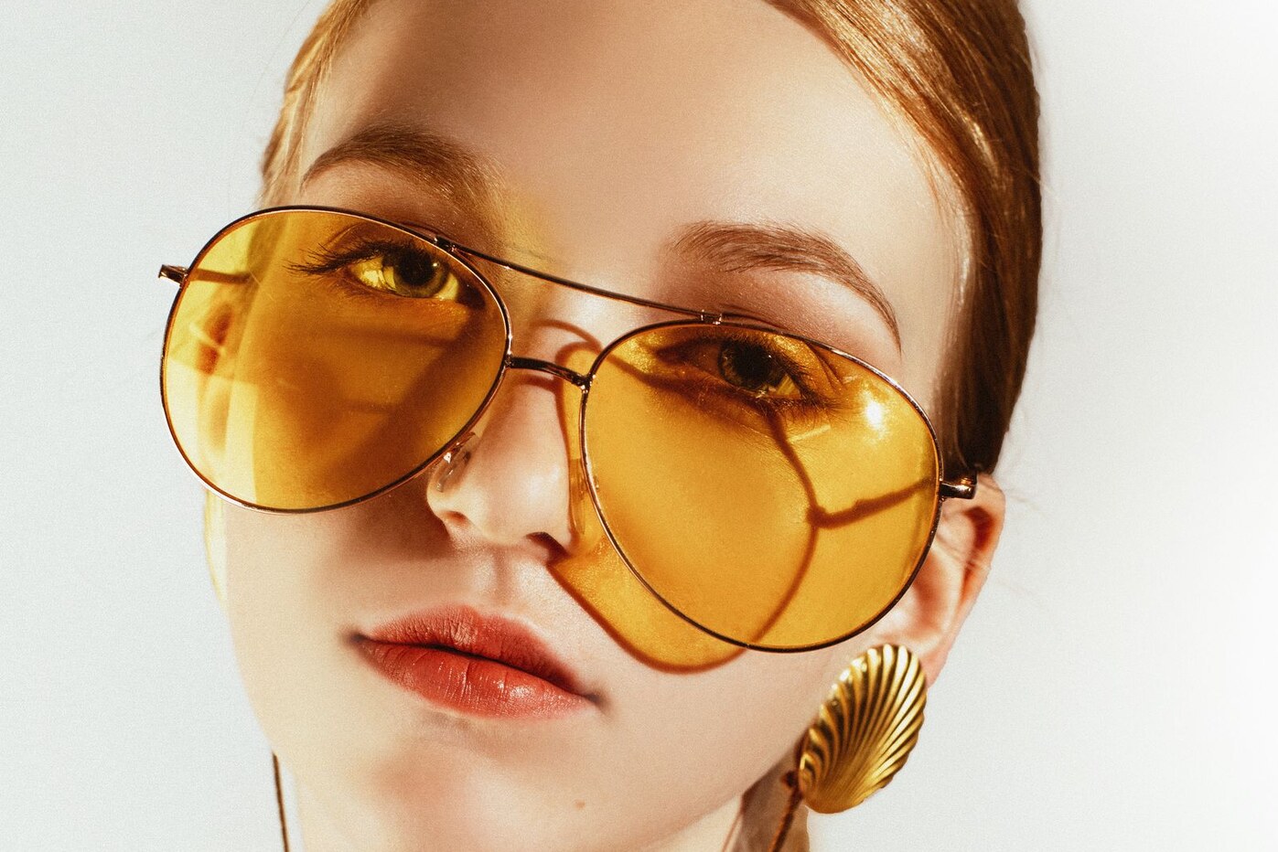 Close-up portrait of a woman wearing amber aviator sunglasses